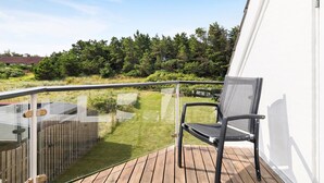 Ein Balkon mit Holzboden, Glasgeländer und einem schwarzen Stuhl.