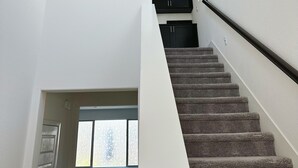 A staircase leading to a second floor with a view of the outside through a window.