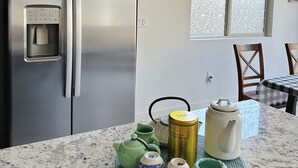 A kitchen with a stainless steel refrigerator, a water dispenser, and a dining area with a table and chairs.