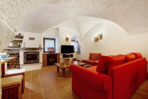 Ein Wohnzimmer mit einem roten Sofa, einem Kamin, einem Fernseher und einer Küchenzeile mit Fliesenboden.
