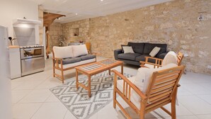 A living room with a stone wall, a sofa, a coffee table, and wooden chairs. - Authentic Charm in the Heart of Brantôme’s Historic Center (Brantôme en Périgord)