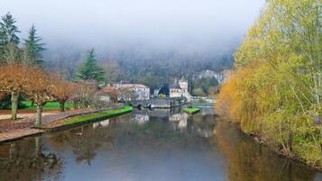 A calm river with a bridge, trees, and buildings in the background.