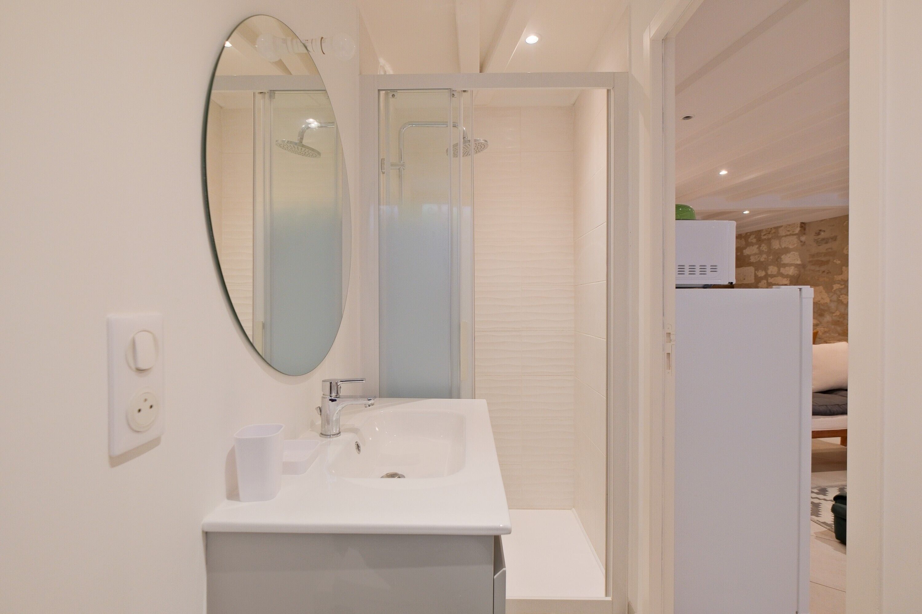 A modern bathroom with a white sink, mirror, and shower.