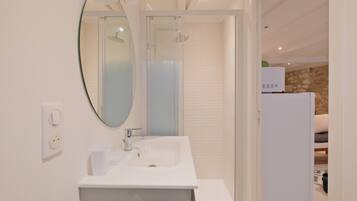 A modern bathroom with a white sink, mirror, and shower.