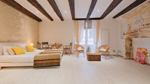 A bedroom with a bed, two chairs, a table, a fireplace, and a window. - Authentic Charm in the Heart of Brantôme’s Historic Center (Brantôme en Périgord)