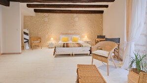 A bedroom with a bed, two chairs, a bedside table, a lamp, and a potted plant. - Authentic Charm in the Heart of Brantôme’s Historic Center (Brantôme en Périgord)