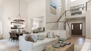 A spacious living room with a white sofa, a wooden coffee table, and a staircase leading to an upper level. - Luxury Home - Walk to Arrow Bahn Lift - 6-Bedrooms with 4 Kings & Game Room (Edwards)