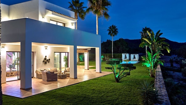 Una casa moderna con patio, mobiliario exterior y piscina.