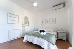 Une chambre à coucher comprenant un lit, une commode, un miroir et des œuvres d’art accrochées au mur.