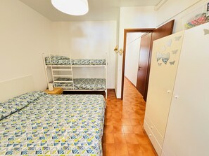 Un dormitorio con literas, un armario y una puerta que da a otra habitación.