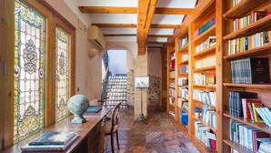 Una biblioteca amb prestatges de llibres, un escriptori de fusta i un globus.