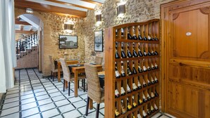 Un celler de vi amb prestatges de fusta, parets de pedra i un sòl de rajola.