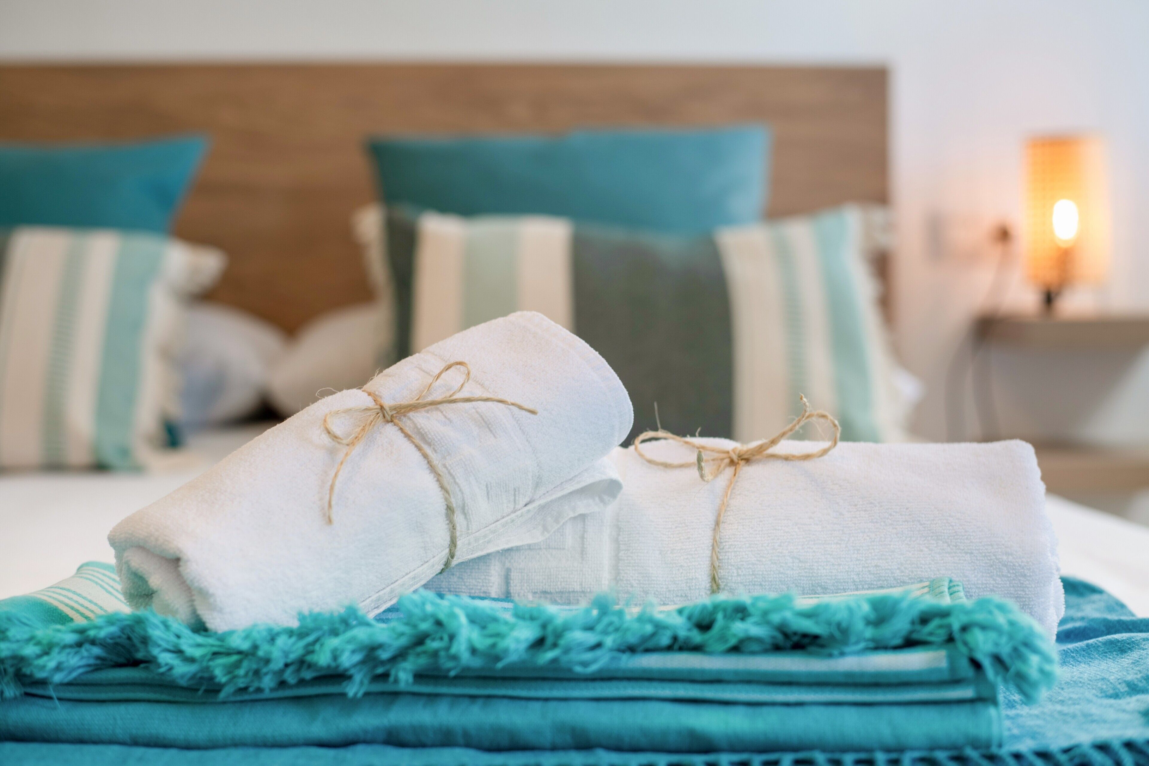Cama bem arrumada com toalhas dobradas e um cobertor azul.
