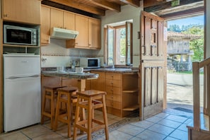 Une cuisine dotée de meubles en bois, d’un four à micro-ondes, d’un réfrigérateur et d’une fenêtre donnant sur l’extérieur.