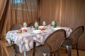 Une table à manger dressée avec des assiettes, des verres et des bouteilles, entourée de chaises.