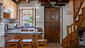 A kitchen with wooden cabinets, a microwave, a sink, and a dining area with stools.