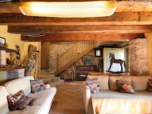 A cozy interior with a wooden staircase, a stone wall, and a horse statue.