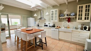 A kitchen with white cabinets, a wooden table, and a dining area with chairs. - Holiday Home 'Villa Betty' with Sea View, Wi-Fi and Air Conditioning (Dénia)