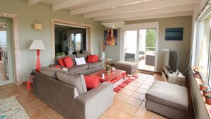 A living room with a sofa, ottoman, coffee table, lamp, TV, and potted plants. - Holiday Home 'Villa Betty' with Sea View, Wi-Fi and Air Conditioning (Dénia)