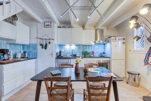 Una cucina moderna con mobili bianchi, un tavolo da pranzo con sedie e una finestra con persiane.