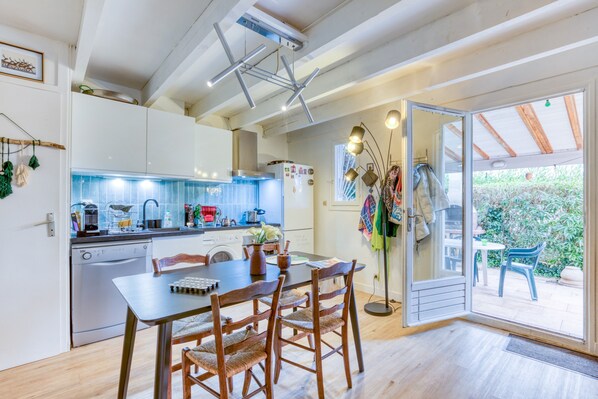 Una cucina moderna con mobili bianchi, un tavolo da pranzo con sedie e una porta scorrevole in vetro che dà su un patio esterno.