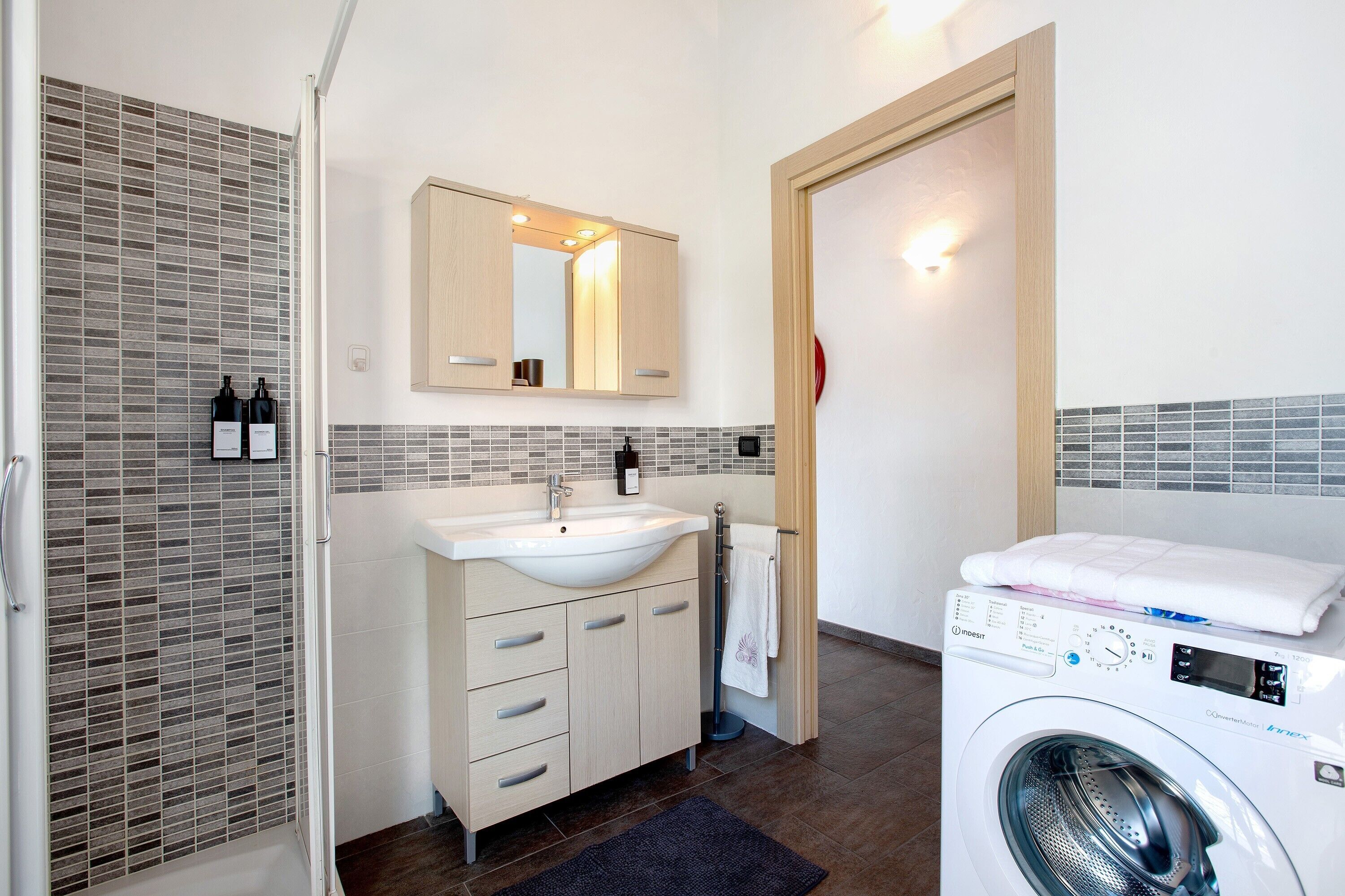 Een moderne badkamer met een wastafel, spiegel en een wasmachine.