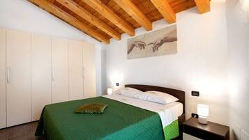 A bedroom with a bed, nightstands, a wooden ceiling, a painting, and a wardrobe.