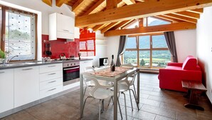 Une cuisine moderne avec des poutres en bois, un coin repas avec une table et des chaises, et un canapé rouge.