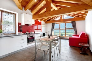 Eine moderne Küche mit Holzbalken, ein Essbereich mit Tisch und Stühlen sowie ein rotes Sofa.