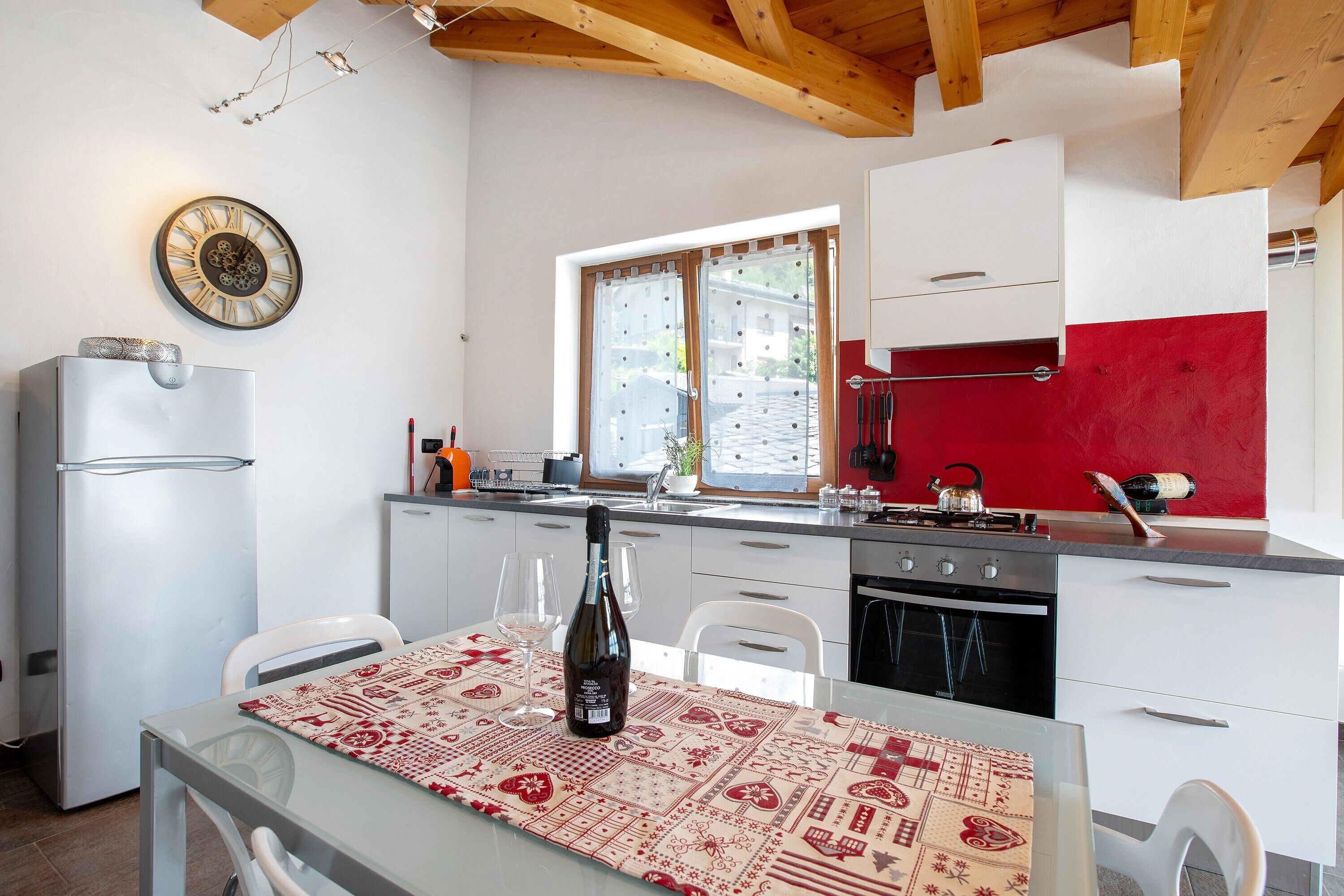 Une cuisine équipée d’un réfrigérateur, d’une cuisinière et d’une table à manger, avec une bouteille de vin.