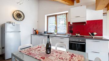 Une cuisine équipée d’un réfrigérateur, d’une cuisinière et d’une table à manger, avec une bouteille de vin.