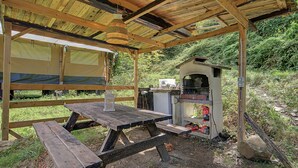Una estructura de madera al aire libre con una mesa de picnic y una parrilla.