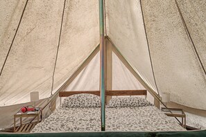 A tent with a bed, a wooden frame, and a pole in the center. - Glamping C Selva Tenda Quercia with BBQ, Shared Pool, and Wi-Fi (Bene Lario)