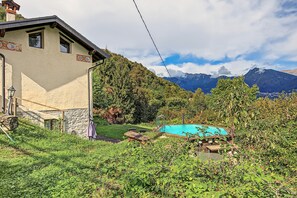 Una casa con un muro de piedra, una terraza de madera y una piscina rodeada de vegetación.