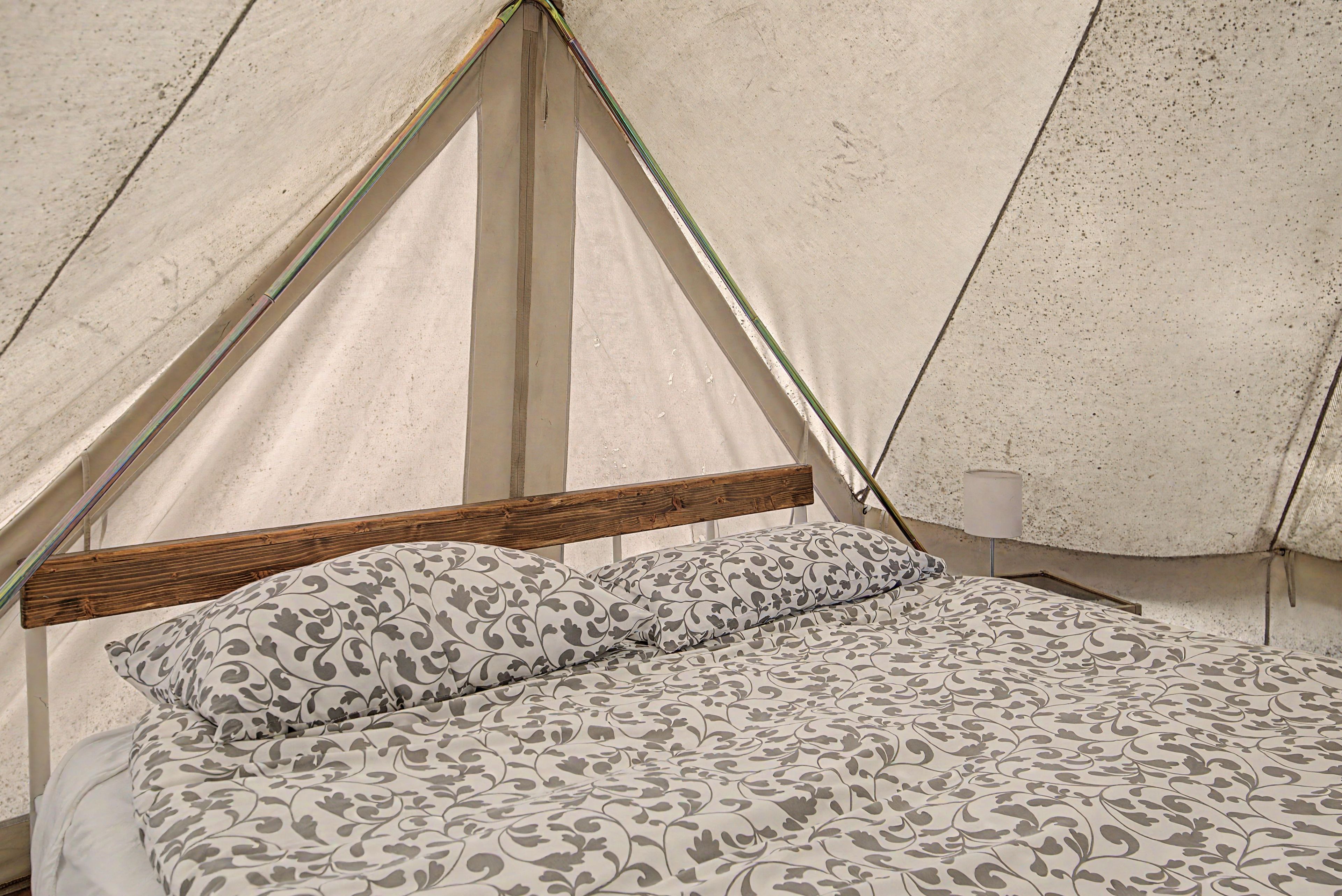 Una tenda con struttura in legno e un letto con biancheria da letto fantasia.