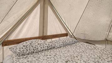 Una tenda con struttura in legno e un letto con biancheria da letto fantasia.