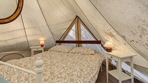 Une chambre à coucher avec un lit, une table de chevet, une lampe et une fenêtre.