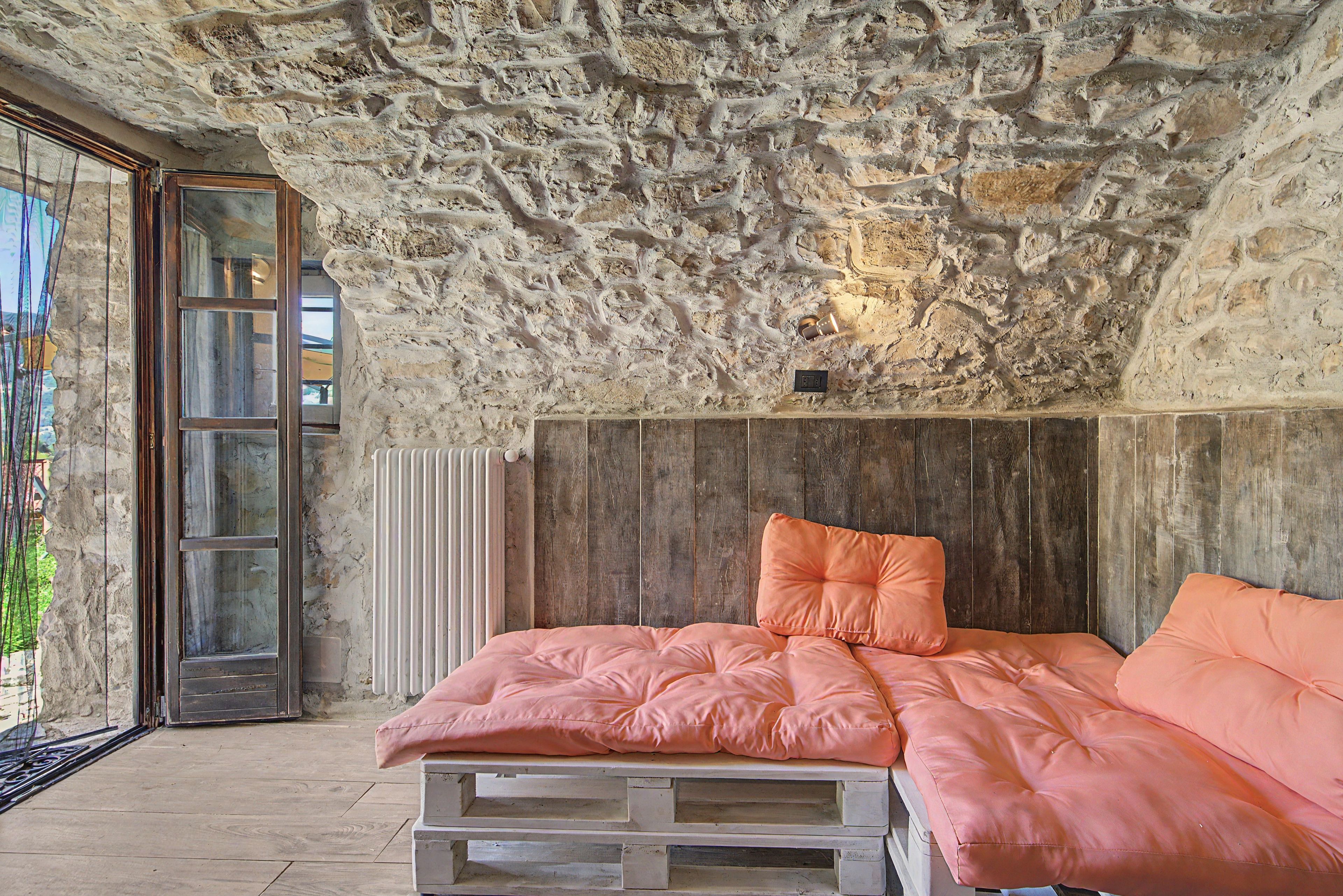 A bedroom with a stone ceiling, a wooden bed frame, and a pink bedspread.