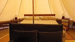Une tente équipée d’un lit, de tables de chevet et d’un canapé.