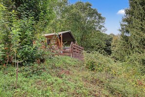 Un chalet rustique doté d’un toit en pente, entouré d’une végétation luxuriante.