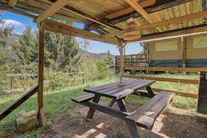 Un pavillon rustique en bois, doté de tables de pique-nique et d’un luminaire suspendu.
