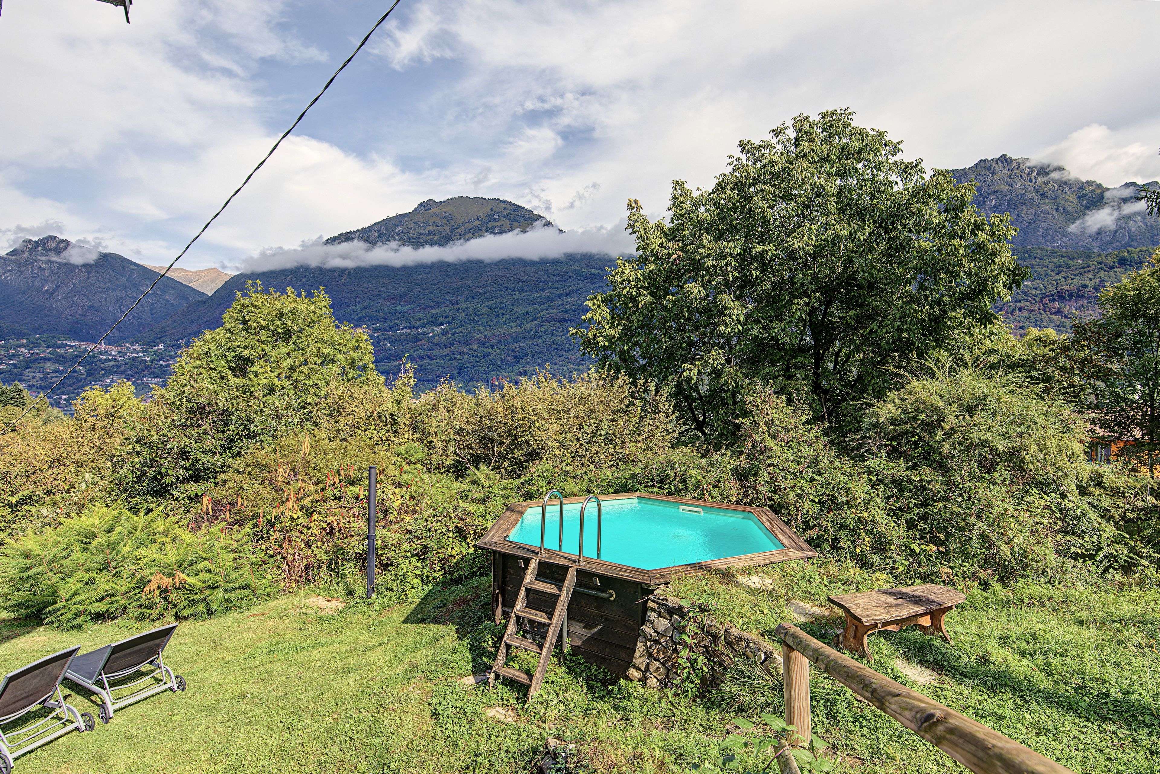 Ein Pool, umgeben von üppiger Vegetation, mit Bergen im Hintergrund.