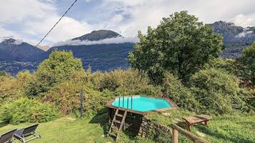 Ein Pool, umgeben von üppiger Vegetation, mit Bergen im Hintergrund.