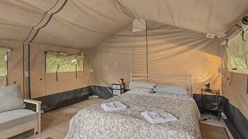A tented room with a bed, a chair, and a small table.