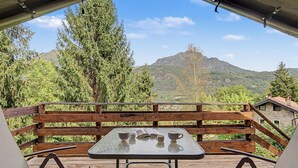 Un espace extérieur aménagé avec une table et des chaises, offrant une vue sur un paysage montagneux.