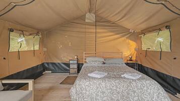 Una habitación con carpa, una cama, mesitas de noche y una ventana.