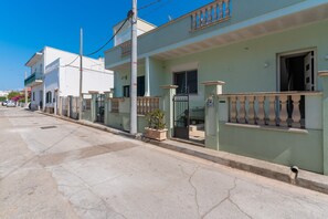 Une rue résidentielle bordée de maisons, avec un ciel dégagé et un poteau électrique bien visible.