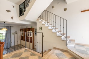 Un intérieur moderne avec un escalier, une balustrade en verre et un sol à carreaux.