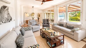 A spacious living room with a sofa set, a coffee table, and a ceiling fan. - Villa 'Gran Cerca De Puerto Banús' with Mountain Views, Wi-Fi, and Air Conditioning (Marbella)