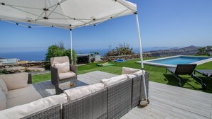 Een terras met tuinmeubilair, een zwembad en uitzicht op zee.